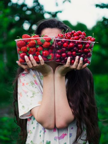 a woman balances berries in her hands